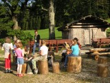 Kinder sitzen auf Holzhockern und haben Spaß.