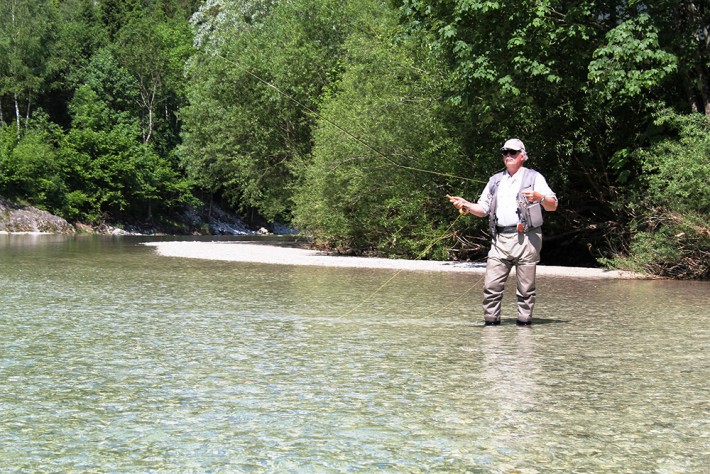Ein Mann steht im seichten Wasser in der Ybbs und tut Fliegenfischen.